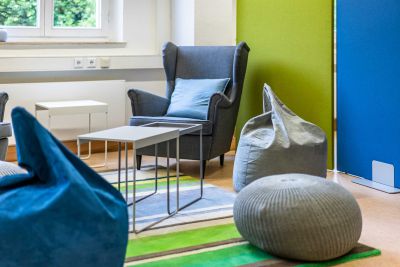 Bunte Loungelösung mit Sitzpouf, Sitzsäcken und Sessel und diversen Beistelltischen